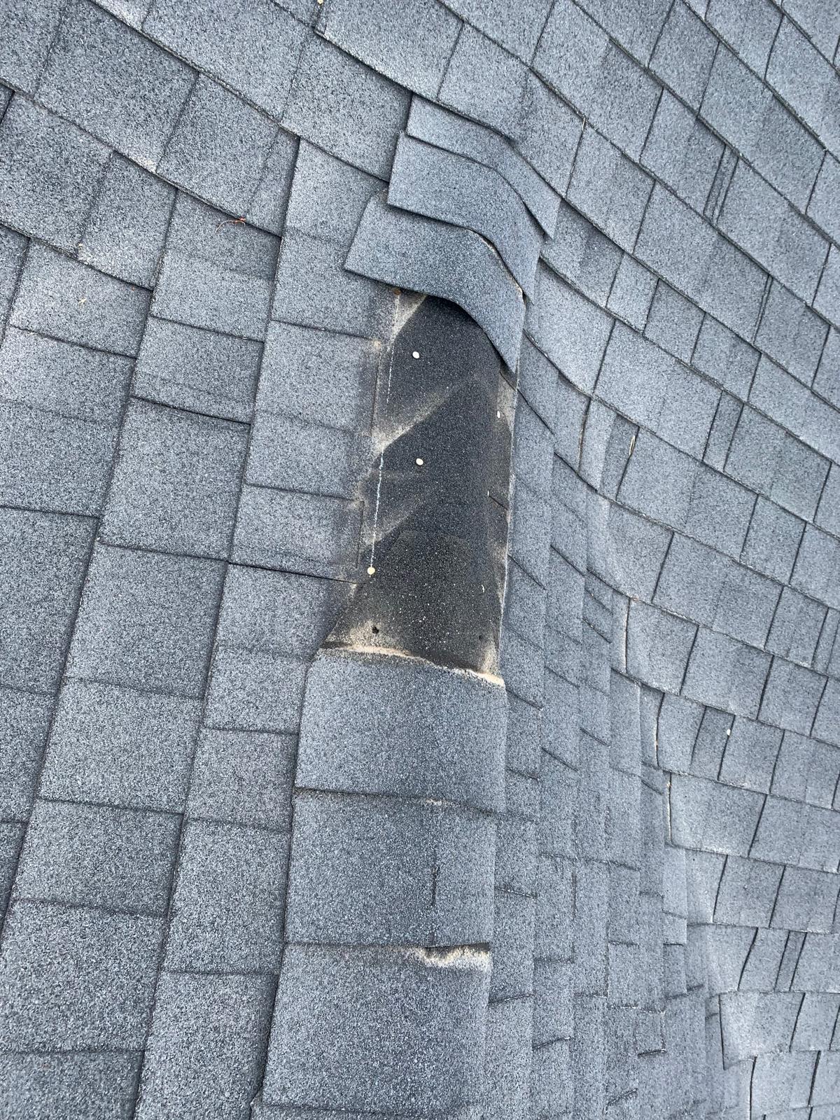 Wind damaged torn shingles signaling roof restoration repair